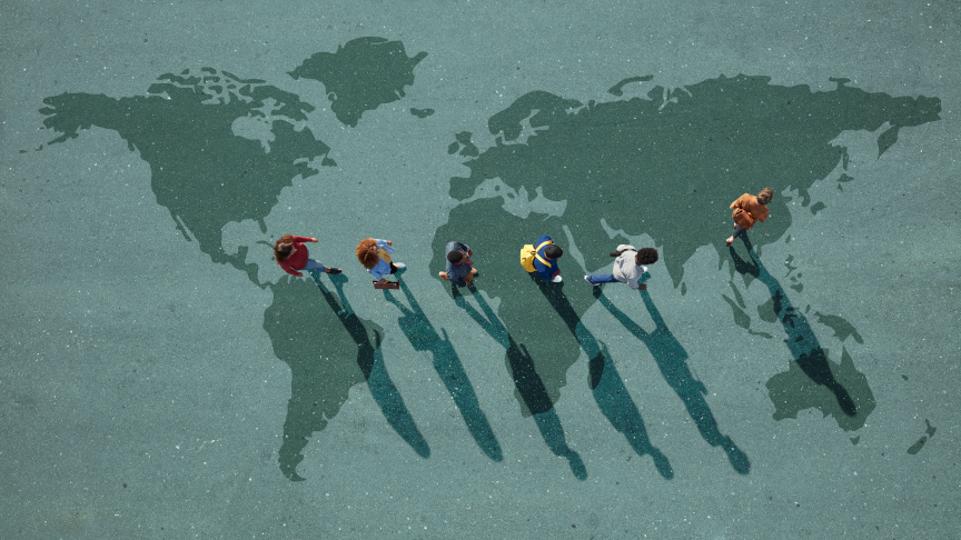 Blick von oben auf internationale Studierende, die in einer Reihe über die Weltkarte, auf Asphalt gemalt, gehen.